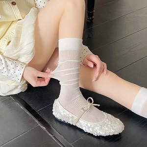 Detail of white striped knee-high sheer socks paired with white Mary Jane flats