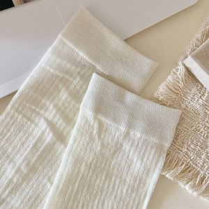 Close-up of cream-white ribbed knit leg warmers with detailed vertical stripe texture