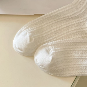 Nahaufnahme von weißen Lolita-Spitzensocken mit hohler Strickstruktur und Blumenmuster