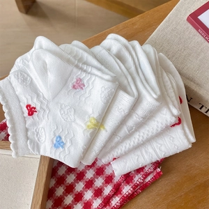 Detail of white cotton socks featuring hollow-out lace patterns and colorful bow embroidery