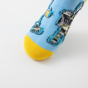 Detailed macro view of cotton sock featuring cartoon excavator embroidery and patchwork texture