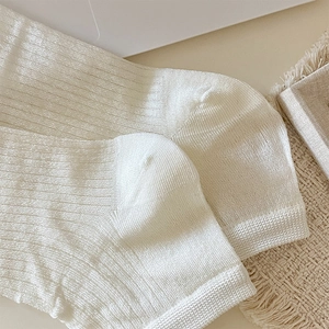 Detail of cream white ribbed knit leg warmers showing high elastic fabric texture