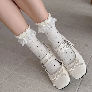 Détail de chaussettes Lolita blanches à pois noirs avec bordure en dentelle et nœuds