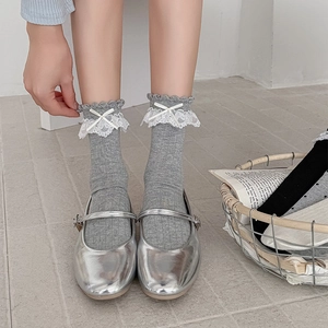 Détail de chaussettes grises côtelées avec volants en dentelle blanche et nœud satin