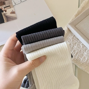 Close-up of ribbed knit leg warmers in black, grey and white with cotton texture