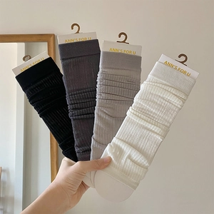 Close-up of four ribbed knit leg warmers in black, grey, and white with hanging cards