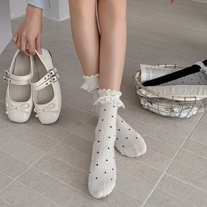 Détail de chaussettes blanches à dentelle avec pois noirs et nœud en satin doux