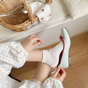 Detail of white lace socks with floral embroidery paired with blue Mary Jane shoes