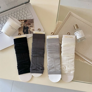 Flat lay of ribbed knit leg warmers in black and grey tones with retail packaging