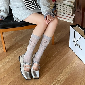 Detail of silver Mary Jane flats with double straps and grey vertical striped leg warmers