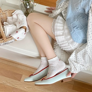 Close-up of white lace socks with red floral embroidery and blue Mary Jane shoes