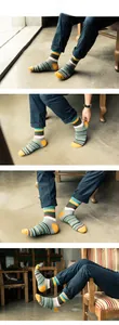 Detailed view of colorful striped mid-calf socks with ribbed cuffs on wooden furniture