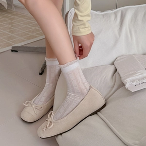 Calze bianche con volant in pizzo a trecce abbinate a ballerine beige in ambiente interno