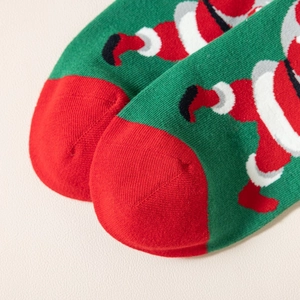 Dettaglio calzini natalizi verdi e rossi con motivi festosi di Babbo Natale