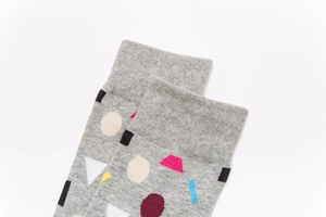 Detail of light grey cotton socks with colorful geometric patterns and ribbed cuffs