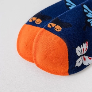 Détail de chaussettes en coton bleu marine avec motifs papillons et pointe orange vif