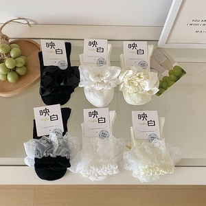 Flach liegende Detailansicht von Lolita-Spitzensocken in Schwarz und Weiß mit Seidenstruktur