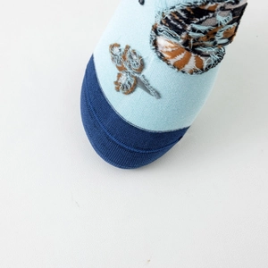 Detail of light blue cotton crew socks featuring intricate moth embroidery and fuzzy texture