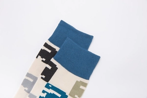 Close-up of cream cotton socks featuring retro pixelated dinosaur patterns and blue ribbed cuffs