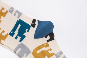 Detail of breathable cream cotton socks with pixelated 8-bit dinosaur patterns and blue heel