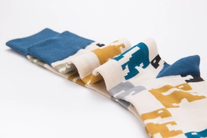 Close-up of stacked breathable cotton socks featuring colorful pixelated animal patterns