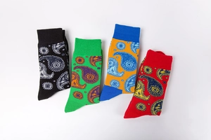 Close-up of four paisley patterned crew socks in black, green, orange and red colors