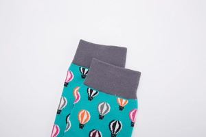 Close-up of turquoise crew socks with colorful hot air balloon patterns and grey ribbed cuffs