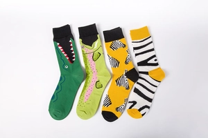 Detail of four colorful crew socks featuring animal patterns like crocodiles and zebras