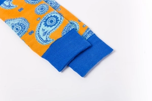 Detail of paisley pattern knitting and blue ribbed cuff on the bright orange sock