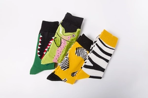 Detail of four creative knitted socks with cartoon crocodile, fish, and zebra patterns