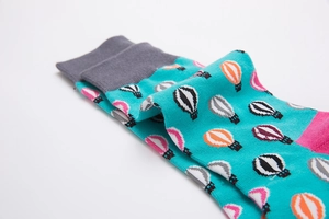 Macro detail of blue mid-calf cotton socks with colorful hot air balloon patterns