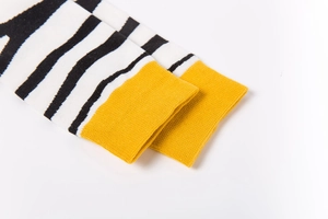 Macro view of black and white striped knit socks with bright yellow ribbed cuffs detail