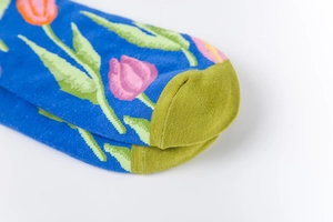 Close-up of knit socks with blue floral patterns and olive green contrast toe design