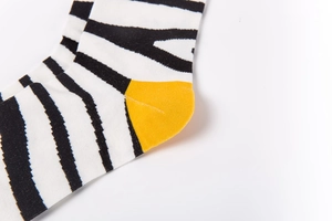 Macro detail of black and white striped cotton socks with vibrant yellow contrast heel