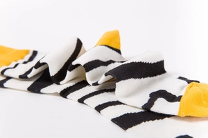 Detail of knit socks featuring classic black and white stripes with yellow heel and toe accents