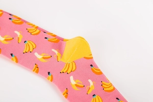 Detailed macro view of pink mid-calf socks featuring yellow banana prints and cotton texture
