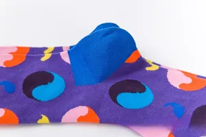 Vue détaillée de chaussettes en tricot violettes avec pois colorés et talon bleu contrasté