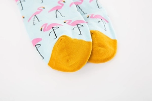 Detailed macro of blue crew socks with pink flamingo patterns and yellow toe detail