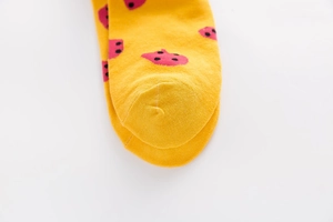 Close-up of strawberry pattern embroidery and fine stitching on yellow cotton socks