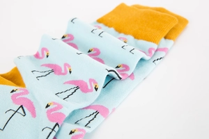 Detail of light blue cotton socks with pink flamingo patterns and mustard yellow cuffs