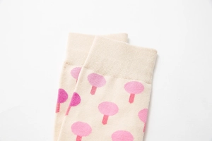 Close-up of ribbed cuffs and pink tree pattern on beige cotton blend mid-calf socks