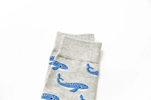 Detail of gray cotton crew sock featuring blue cartoon whale patterns and ribbed cuffs