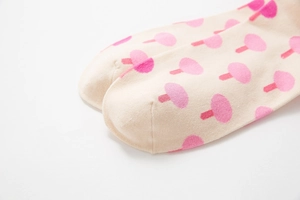 Close-up of pink mushroom pattern on soft beige cotton socks with detailed stitching
