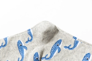 Detail of soft cotton blend knit socks with a cute blue cartoon whale pattern on gray