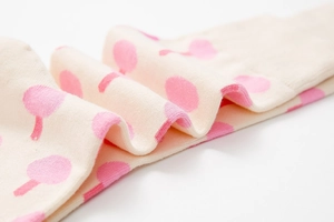 Detailed macro view of cream-colored knit socks with soft pink mushroom patterns