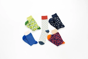 Flat lay of five colorful crew socks with lemon, dot, and geometric patterns on white background