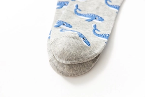Macro shot of gray cotton socks featuring blue whale patterns and precise toe stitching