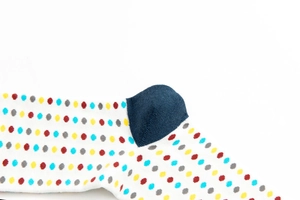 Detail of colorful polka dot pattern and navy blue heel on white knit crew socks