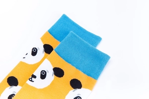 Macro detail of ginger yellow cotton socks with panda print and blue ribbed cuffs