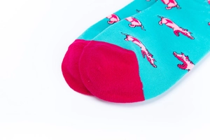 Nahaufnahme der türkis gestrickten Socke mit pinkem Welpenmuster und pinker Spitze